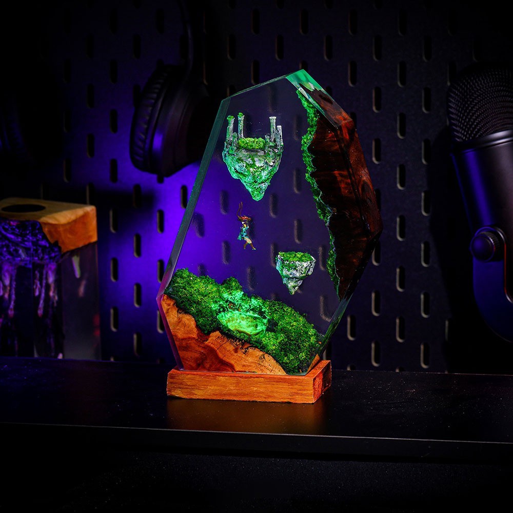 Sky Isles Resin Lamp glowing green on a dark gaming desk beside headphones and a microphone