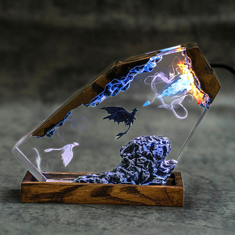 Fire & Frost Dragon Resin Lamp lit in a dark room, black and white dragons in clear resin on a wood base
