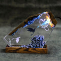 Fire & Frost Dragon Resin Lamp lit in a dark room, black and white dragons in clear resin on a wood base